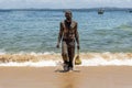 Man covered in oil on the beach at Porto da Barra in Salvador, Bahia, Brazil