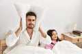 Man covering ears with pillow irritated for snore lying in bed at home Royalty Free Stock Photo