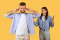 Man covering ears, woman arguing, communication breakdown on yellow background