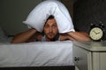 Man covering head with pillow in bed at home Royalty Free Stock Photo