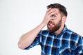 Man covering his face with palm and looking at camera through fingers