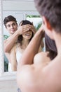 Man covering womans eyes while standing in front of bathroom mirror Royalty Free Stock Photo