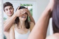 Man covering womans eyes while standing in front of bathroom mirror Royalty Free Stock Photo