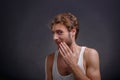 The man covers his mouth with his hand on a black background