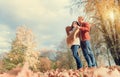 Man covers his wife shoulders with warm shawl in autumn park