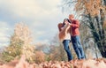 Man covers his wife shoulders with warm shawl in autumn park