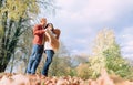 Man covers his wife shoulders with warm shawl in autumn park