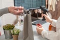 Man with credit card buying gift in a female clothing store. Woman cashier, seller scanning using barcode scanner at the checkout. Royalty Free Stock Photo