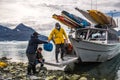 Man with crew members from scientific expedition unload the vessel docked on iceberg rock bay at wintertime to explore the island