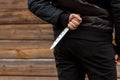 A man, a criminal in black clothes, holds a large knife in his hand. Close-up, copy space. The concept of crime, violation of the