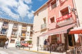 Man crosses street while women enjoy morning drink in shade outside small Spanish village bar