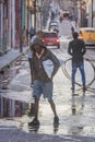 the man is crossing the street in the rain with a fire hose