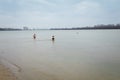 Man crossing and woman standing in water. Christening or baptism bathing in winter river. January rite, religious tradition Royalty Free Stock Photo