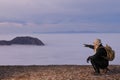 MOUNTAIN MAN WITH BACKPACK POINTING WITH HIS FINGER TO A MOUNTAIN TO OVERCOME FROM THE CLOUDS