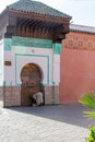 Man crouched next to an Arab door in the city of Marrakech. Morocco