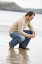 Man crouching on beach Royalty Free Stock Photo