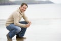 Man crouching on beach Royalty Free Stock Photo