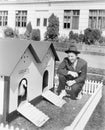 Man crouching next to duck house Royalty Free Stock Photo