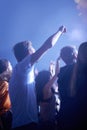 Man in crowd, fans and dancing at concert, music festival and hands in air for energy or night event. Dance, fun or Royalty Free Stock Photo