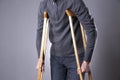 Man on crutches on a gray background Royalty Free Stock Photo