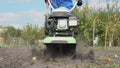 Man cultivates the ground in the garden with a tiller, preparing the soil for sowing