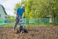Man cultivates the soil in the garden using a motor cultivator - tiller Royalty Free Stock Photo