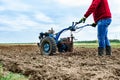 Man cultivating soil with tiller block in spring. Royalty Free Stock Photo