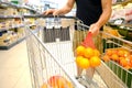 man customer puts grid of oranges in grocery cart in supermarket store, Health-conscious shopping habits, Fresh fruits and Royalty Free Stock Photo
