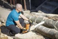 Man cut with saw. Dust and movements. Woodcutter saws tree with chainsaw on sawmill.