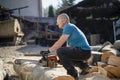 Man cut with saw. Dust and movements. Woodcutter saws tree with chainsaw on sawmill.