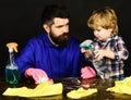 Man with cute child on black. Kid and father with busy faces cleaning together with spray. Parents little helper concept