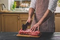 Man cuts of fresh piece of beef on a wooden cutting board in the home kitchen