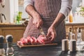 Man cuts of fresh piece of beef on a wooden cutting board in the home kitchen