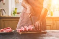 Man cuts of fresh piece of beef on a wooden cutting board in the home kitchen