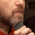 A man cuts his gray beard trimmer Royalty Free Stock Photo