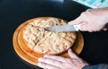 A man cuts a homemade Apple pie lying on a round wooden Board into four parts Royalty Free Stock Photo