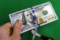 A man cuts a hundred-dollar bill with scissors