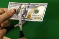 A man cuts a hundred-dollar bill with scissors