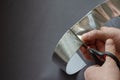 A man cuts off a piece of aluminum tape with scissors. View from above from behind