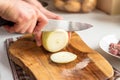 A man cuts onions on a wooden board with a sharp knife Royalty Free Stock Photo