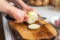 A man cuts onions on a wooden board with a sharp knife Royalty Free Stock Photo