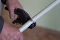 A man cuts a plastic pipe with scissors.