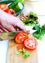 Man cuts ripe tomatoes for summer vegetable salad