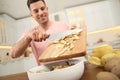 Man with cutting board and knife scraping vegetable peels into bowl