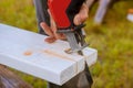 A man is cutting a board of wood with a jigsaw detail of a cutting wooden board with saw dust