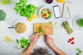 Man cutting celery and cooking vegan fresh salad with vegetables. Blank screen smart phone and notebook for daily diet planning. Royalty Free Stock Photo