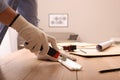Man cutting foam crown molding with utility knife at wooden table indoors, closeup Royalty Free Stock Photo