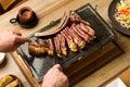 Man cutting a grilled steak with bone on a cooking stone Royalty Free Stock Photo