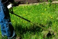 Man cutting grown long grass at yard using grass-cutter at summer time.Lawn