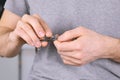 Man is cutting his nails by Clippers. Close-up hands.Grey t-shirt in the background.